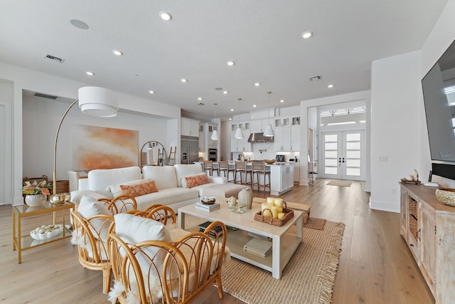 living area with light wood-style floors, french doors, recessed lighting, and visible vents
