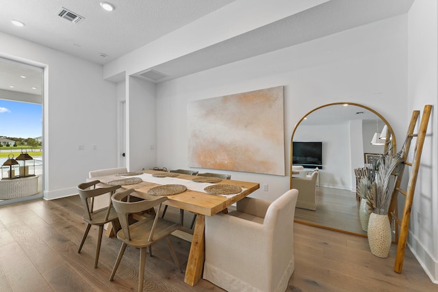 dining space featuring a textured ceiling and wood-type flooring