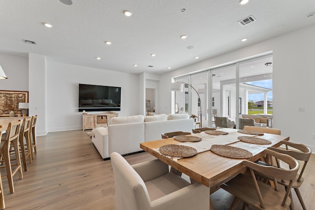 dining room featuring a textured ceiling and light hardwood / wood-style floors