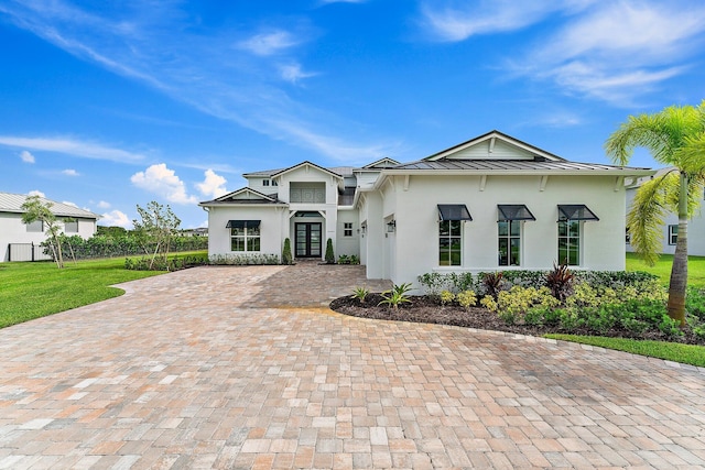 view of front facade featuring decorative driveway, stucco siding, french doors, a standing seam roof, and metal roof