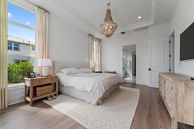 bedroom with ensuite bath, ornamental molding, hardwood / wood-style floors, and an inviting chandelier