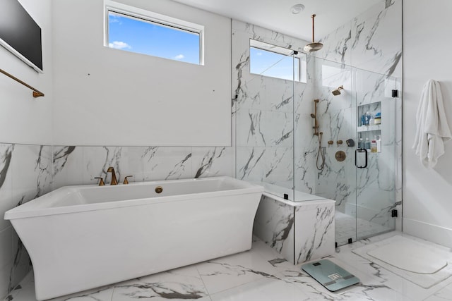 bathroom featuring a freestanding bath, tile walls, a marble finish shower, and marble finish floor