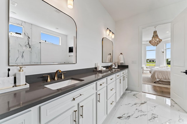 ensuite bathroom with connected bathroom, double vanity, visible vents, and a sink