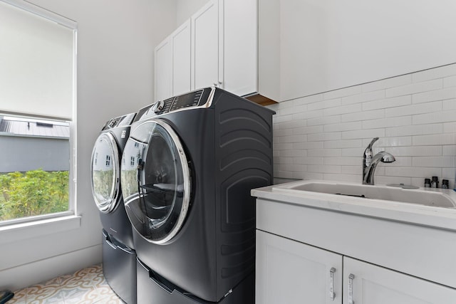 clothes washing area with cabinets, washing machine and dryer, light tile patterned floors, and sink