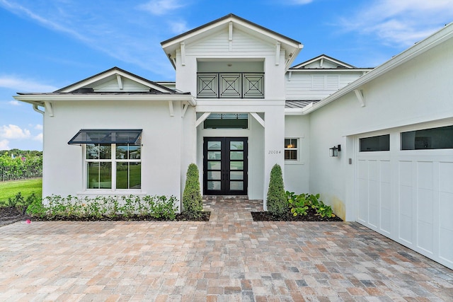 view of exterior entry featuring an attached garage, a standing seam roof, metal roof, and stucco siding