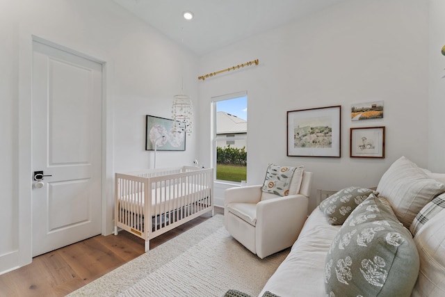 bedroom featuring hardwood / wood-style flooring and a crib