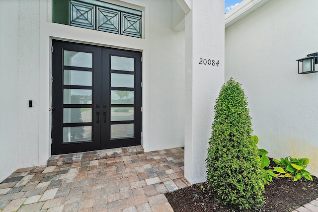 view of exterior entry featuring french doors and stucco siding