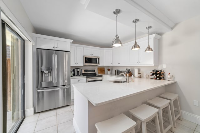 kitchen featuring stainless steel appliances, white cabinets, kitchen peninsula, hanging light fixtures, and a kitchen breakfast bar