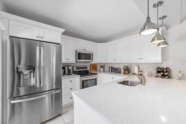 kitchen featuring hanging light fixtures, sink, stainless steel appliances, and white cabinets