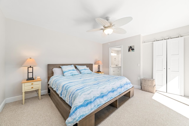 carpeted bedroom featuring a barn door, connected bathroom, and ceiling fan