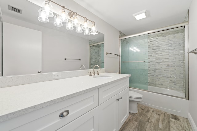 full bathroom with vanity, hardwood / wood-style floors, toilet, and combined bath / shower with glass door