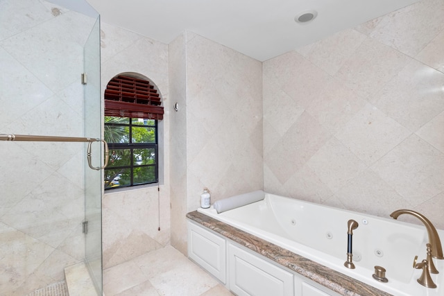 bathroom featuring shower with separate bathtub and tile walls