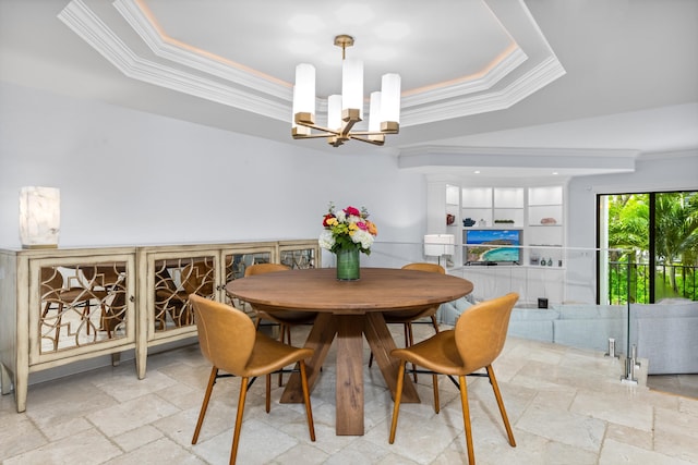 dining space with a raised ceiling, ornamental molding, and a chandelier