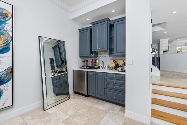 kitchen featuring stainless steel fridge, decorative backsplash, blue cabinetry, ornamental molding, and sink