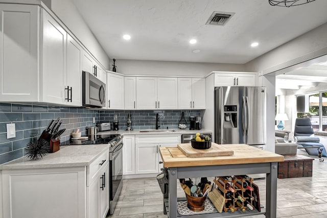 kitchen with stainless steel appliances, a sink, visible vents, light countertops, and decorative backsplash