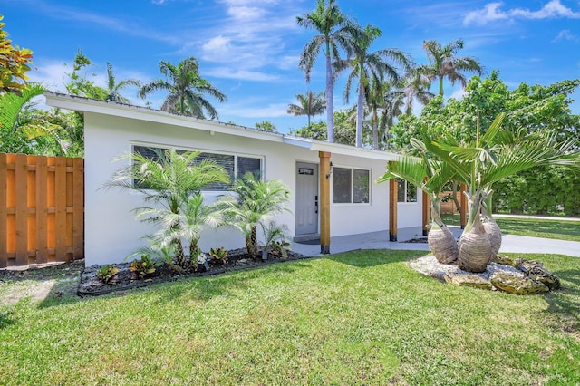 view of front of property featuring fence, a front lawn, and stucco siding