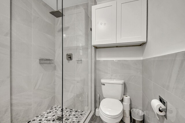 full bathroom featuring toilet, a stall shower, and tile walls