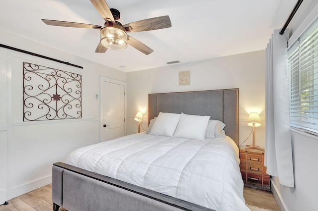 bedroom with ceiling fan, light wood finished floors, visible vents, and baseboards