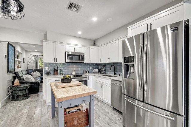 kitchen featuring butcher block counters, visible vents, backsplash, appliances with stainless steel finishes, and a sink