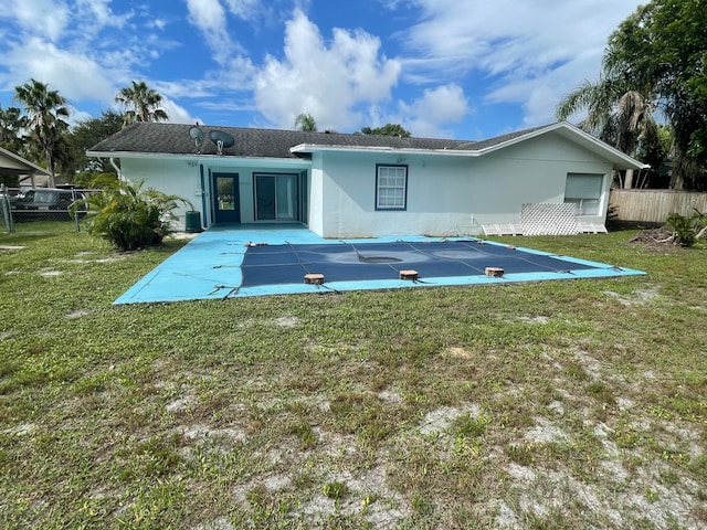 rear view of property with a lawn, a patio area, and a covered pool