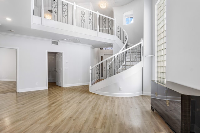 interior space with crown molding, a high ceiling, and hardwood / wood-style floors