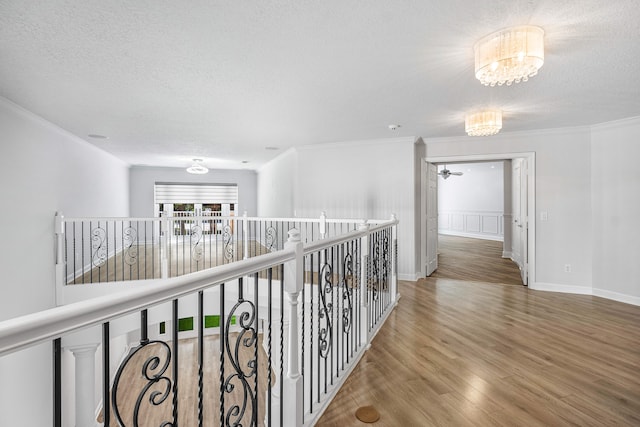 corridor featuring hardwood / wood-style floors, an inviting chandelier, crown molding, and a textured ceiling