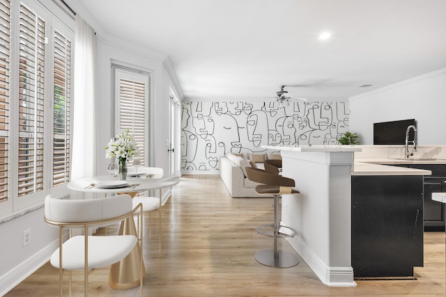 kitchen with ornamental molding, ceiling fan, sink, and light hardwood / wood-style floors