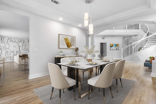 dining area with ornate columns, ornamental molding, and light hardwood / wood-style floors