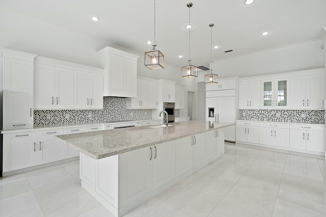 kitchen with paneled built in fridge, a large island with sink, ornamental molding, and white cabinetry