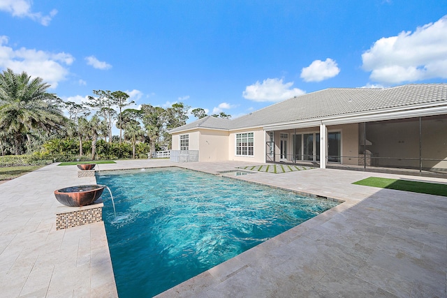 pool with a sunroom, a patio area, and a fire pit