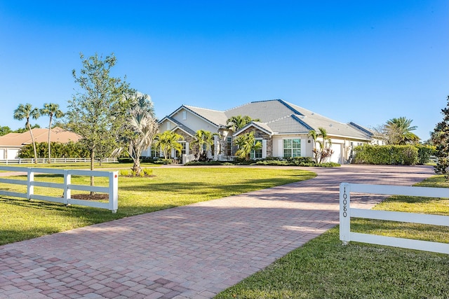 view of front of house with decorative driveway, a front yard, and fence