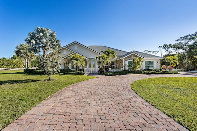 view of front of house featuring a front lawn, decorative driveway, and french doors