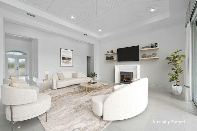 living room featuring visible vents, a tray ceiling, a fireplace, wood ceiling, and french doors