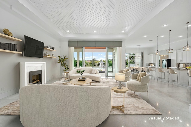 living room featuring recessed lighting, baseboards, a raised ceiling, and a fireplace