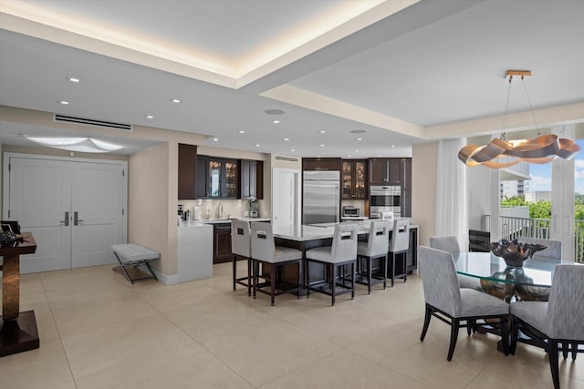 dining room with a raised ceiling, light tile patterned floors, and sink