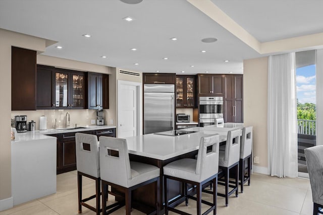 kitchen featuring appliances with stainless steel finishes, a center island, light countertops, and glass insert cabinets