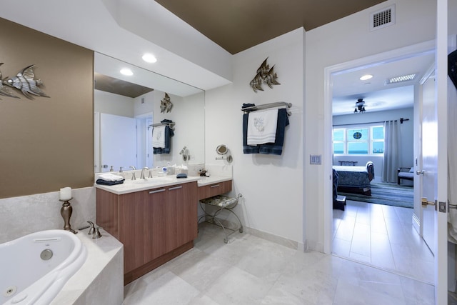 bathroom featuring tiled tub and vanity