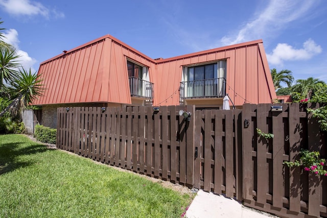 view of front of house featuring a fenced front yard, a front lawn, and mansard roof