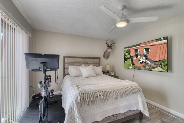 bedroom with a textured ceiling, ceiling fan, wood finished floors, and baseboards