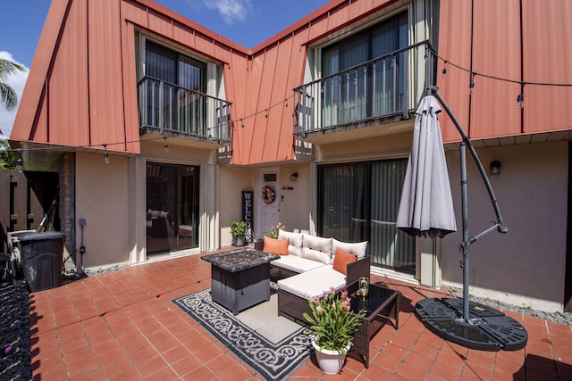 exterior space with mansard roof, a balcony, a patio area, an outdoor living space, and stucco siding