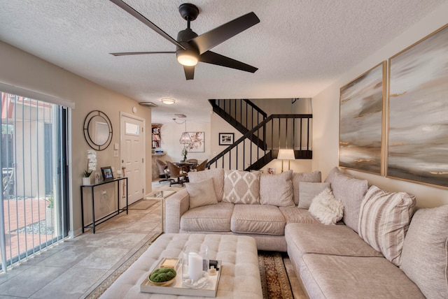 living room featuring ceiling fan, light tile patterned floors, a textured ceiling, and a healthy amount of sunlight