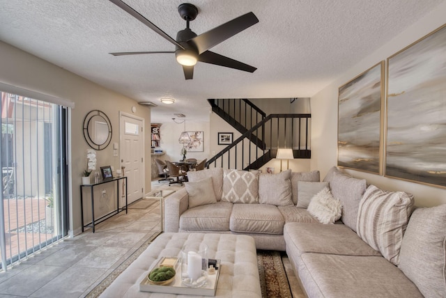 living room featuring a wealth of natural light, ceiling fan, a textured ceiling, and stairs