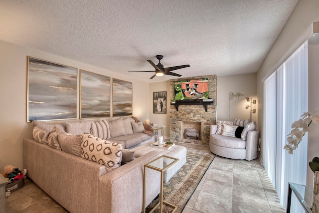 tiled living room with a textured ceiling, ceiling fan, and a stone fireplace