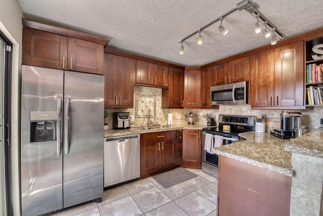 kitchen with a sink, appliances with stainless steel finishes, light stone countertops, open shelves, and tasteful backsplash