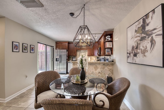 dining room featuring light tile patterned floors, a textured ceiling, baseboards, and an inviting chandelier