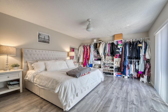 bedroom featuring a textured ceiling, ceiling fan, and wood finished floors