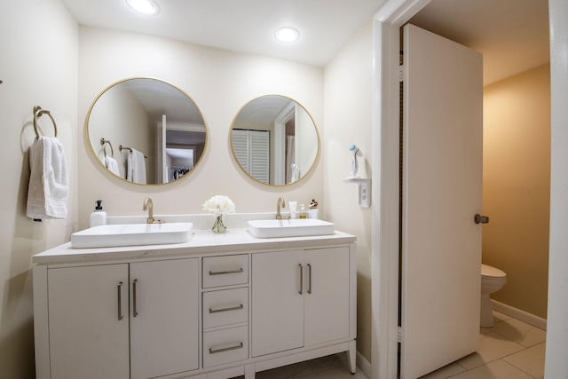 full bath with double vanity, a sink, toilet, and recessed lighting