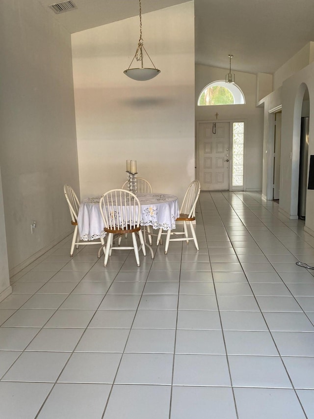 unfurnished dining area with high vaulted ceiling and tile patterned flooring