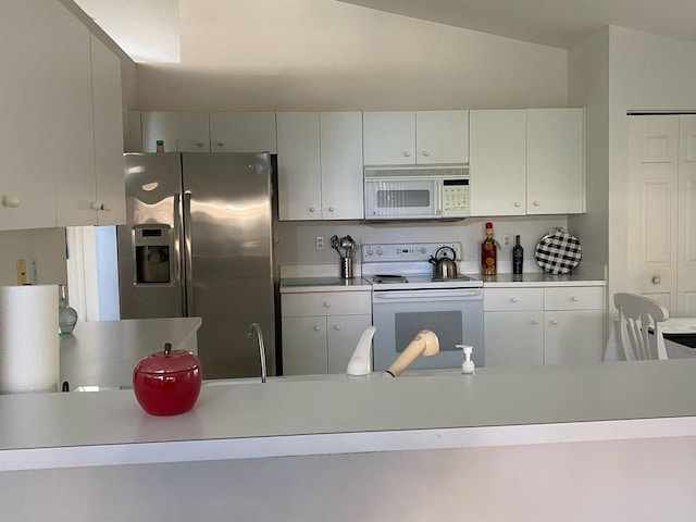 kitchen featuring vaulted ceiling, white cabinetry, and white appliances