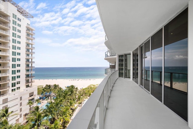 balcony with a water view and a view of the beach